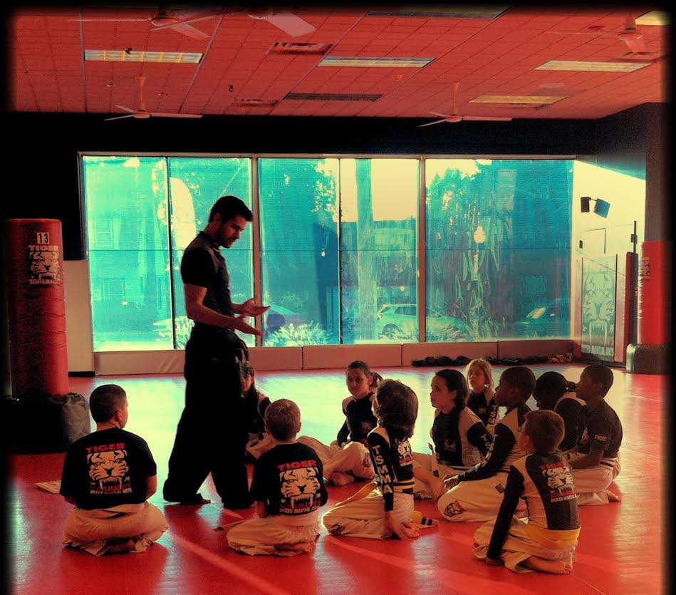Sensei standing and talking kids sitting and listening