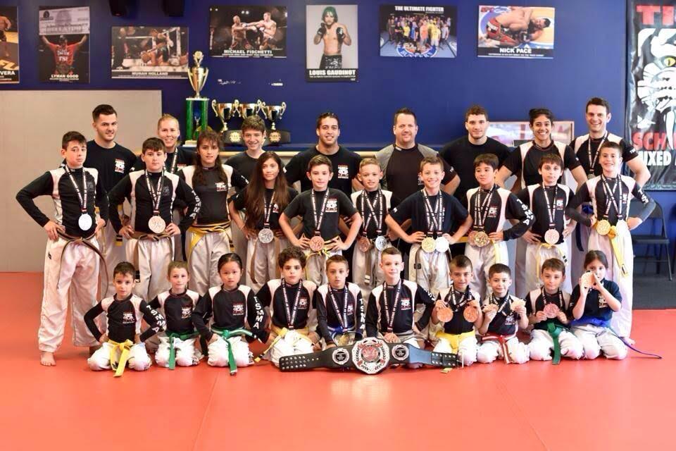 Children martial art fighters posing with medals with Sensei