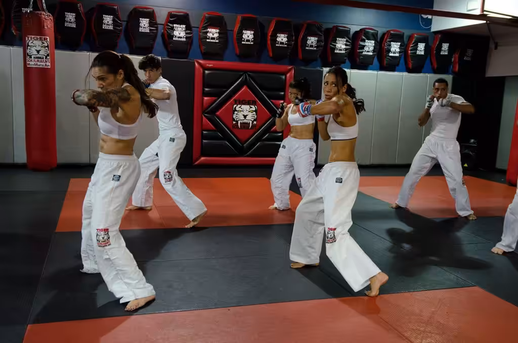 Adult men and women kickboxers in white exercising at Tiger Schulmann's gym