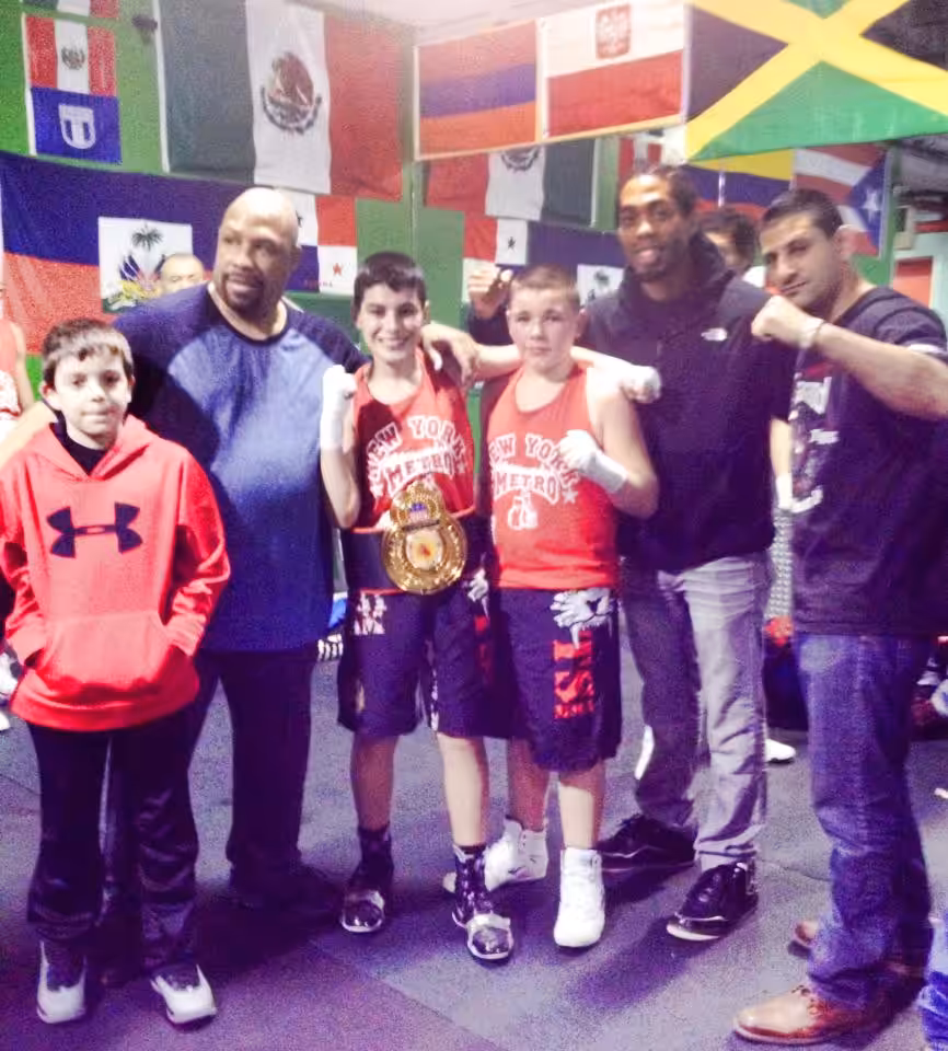 Boy Wearing Championship Belt with his Tiger Schulmann's crew and flags behind them