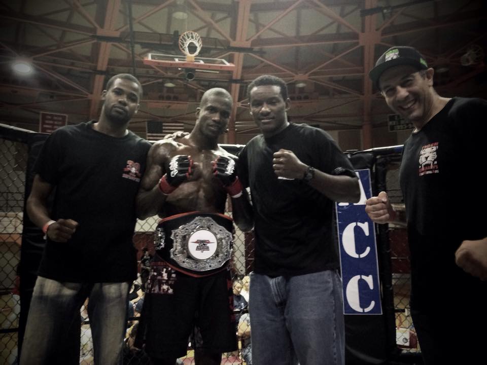 Tiger Schulmann's Champion fighter wearing a winning belt with his crew