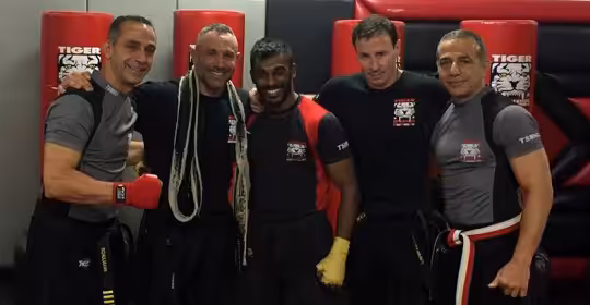 Five MMA fighters posing at Tiger Schulmann's gym