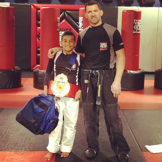 A boy fighter with Championship Belt and his coach at Tiger Schulmann's