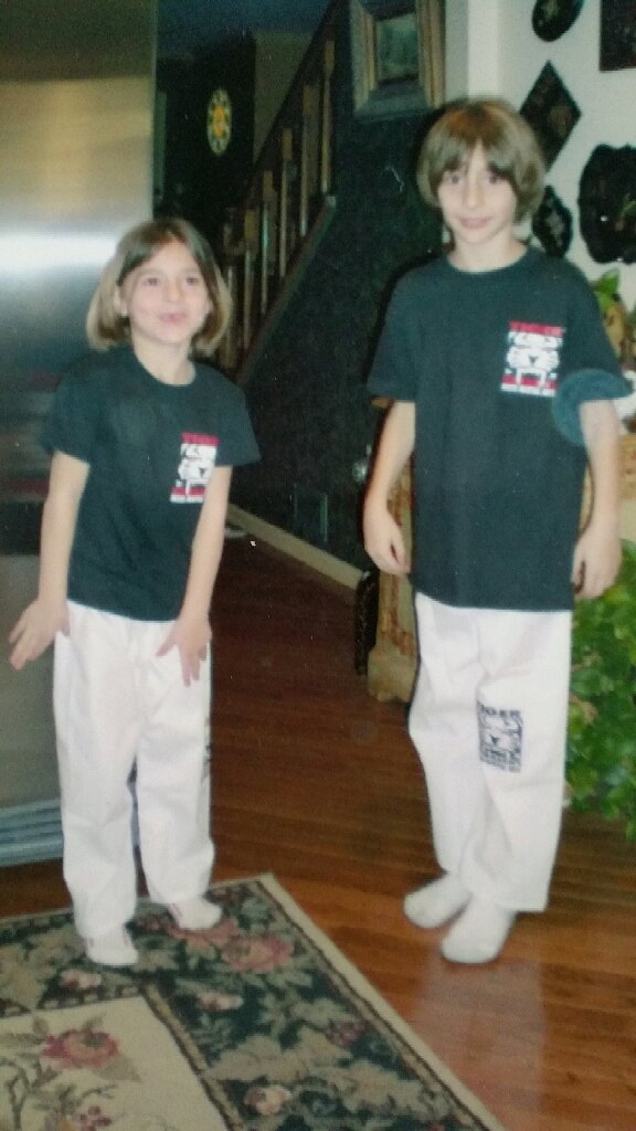 A boy and a girl standing in living room wearing Tiger Schulmann's shirts
