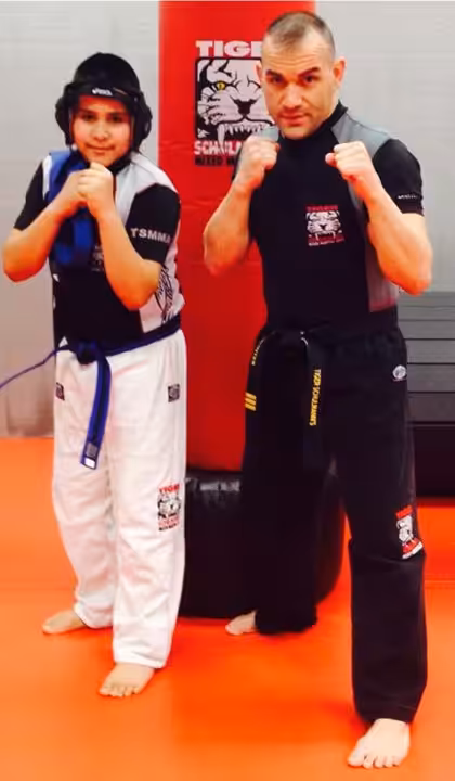 Two Men Punching Pose in front of a punching bag at Tiger Schulmann's Vails Gate