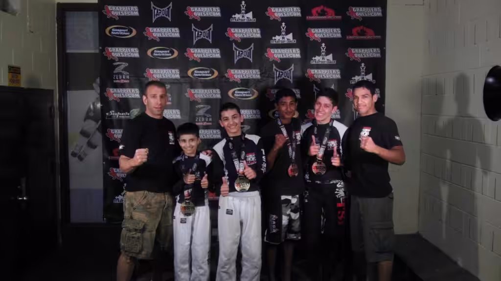 Four boys with medals and two instructors at Tiger Schulmann's