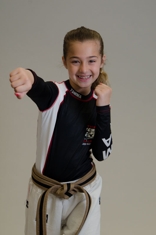 A Girl in a Punching Pose smiling and wearing Tiger Schulmann's gear
