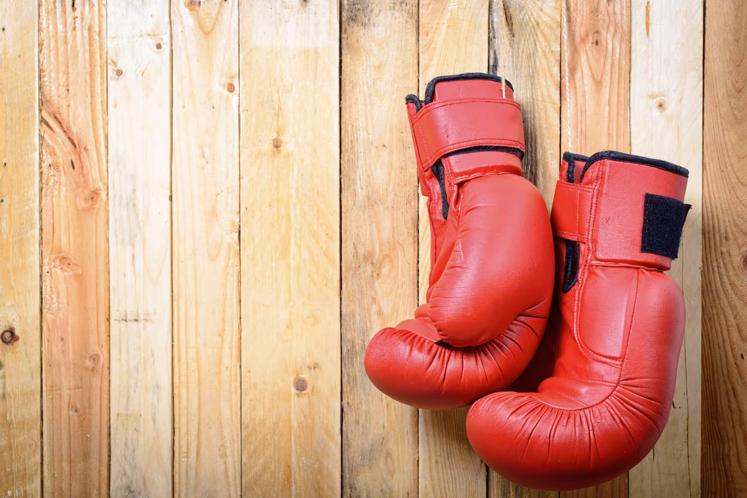Red Boxing Gloves hanging on the wooden boards
