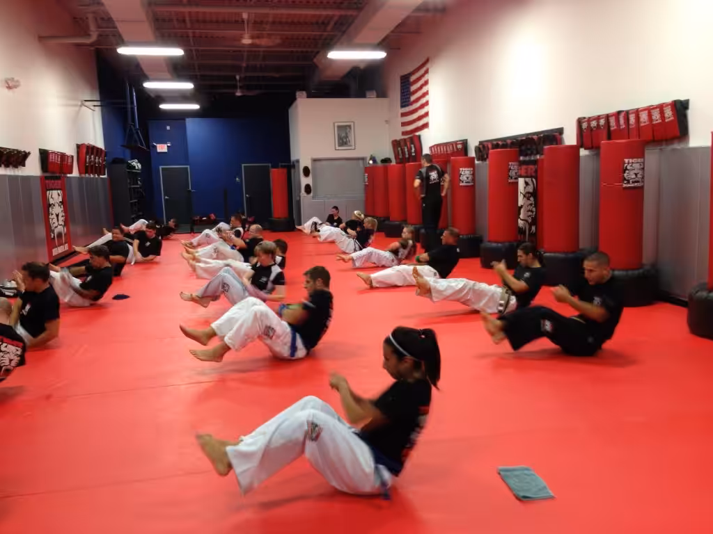 Adult kickboxers doing sit ups on the red gym floor at Tiger Schulmann's
