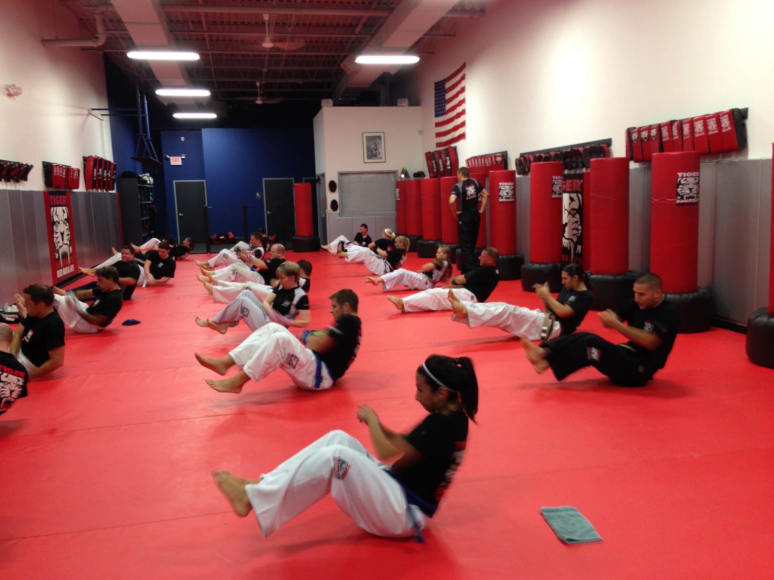 Adult kickboxers doing sit ups on the red gym floor at Tiger Schulmann's