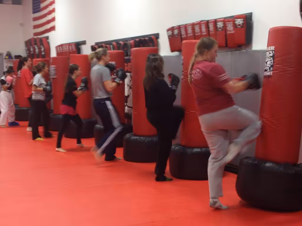 Adult team kickboxing kicking punching bags on the floor at Tiger Schulmann's