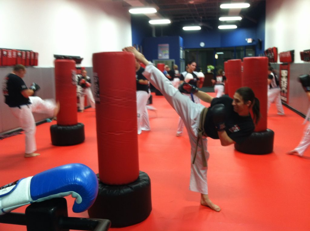 Woman kickboxer practicing kicking with other fighters at Tiger Schulmann's gym