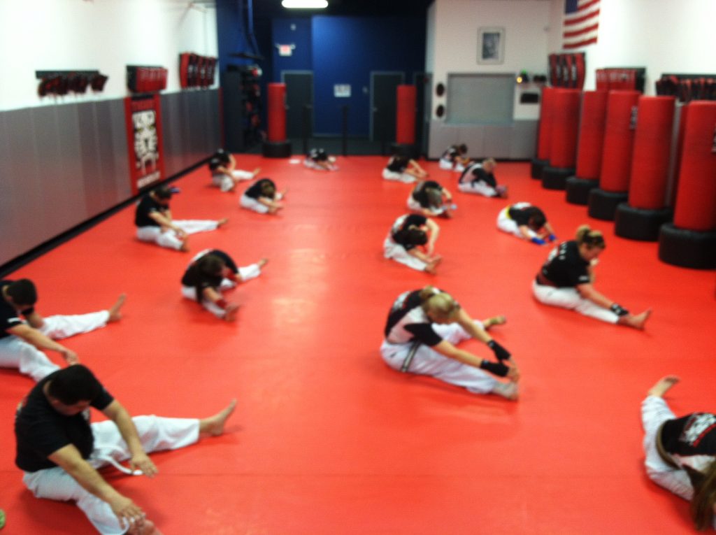 Adult team kickboxing stretching and listening to instructor at Tiger Schulmann's