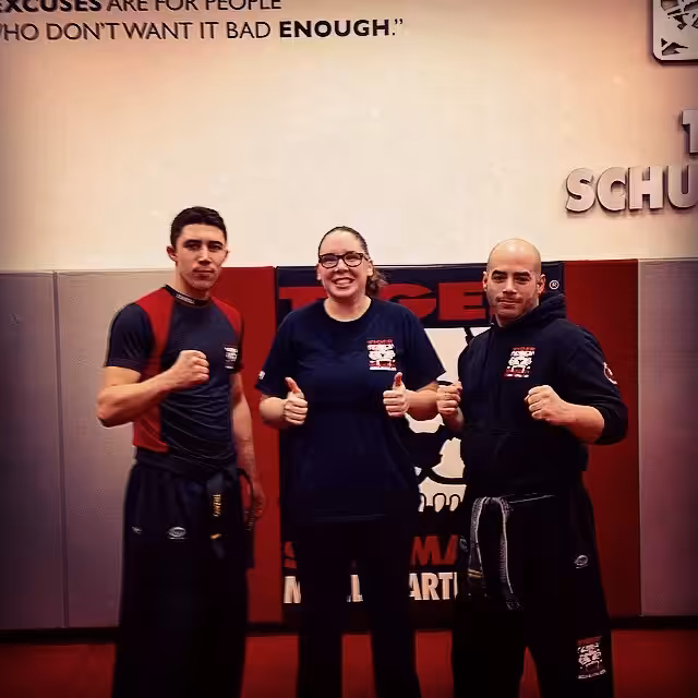 Two men and a woman fighter with thumbs up at Tiger Schulmann's