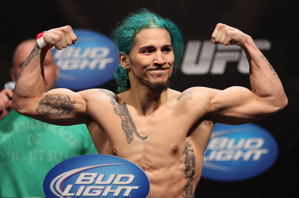 MMA fighter with green hair flexing muscles