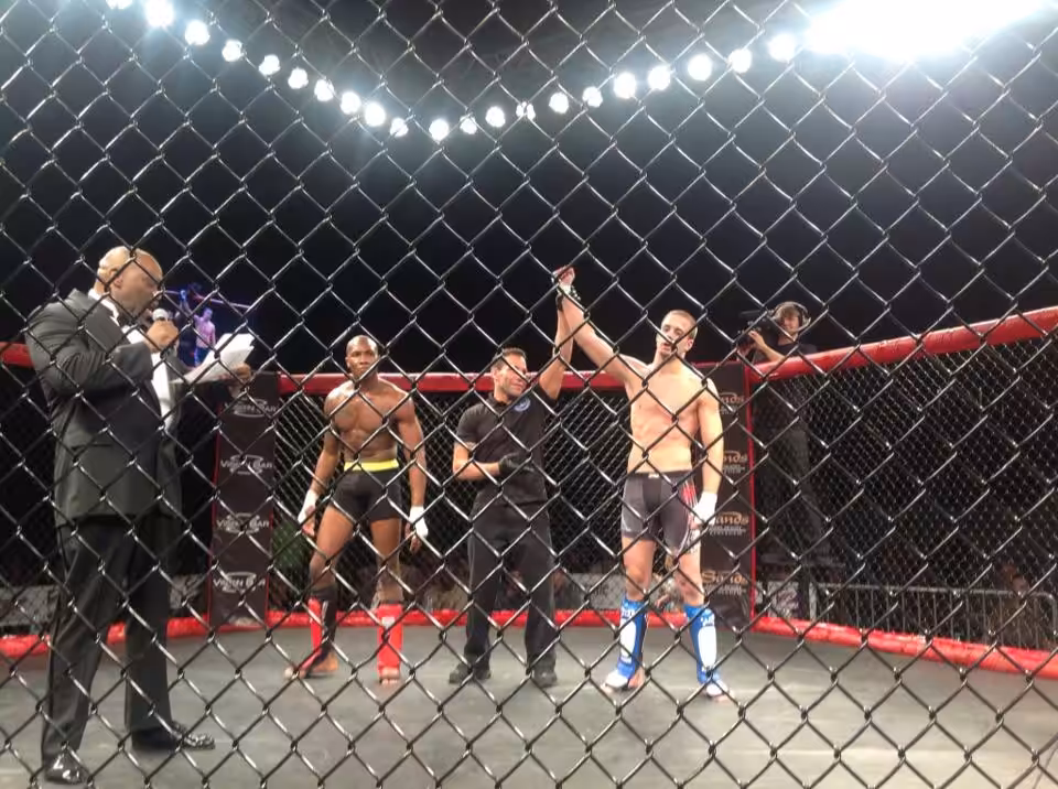 Referee in octagon raises arm of Tiger Schulmann's MMA fighter