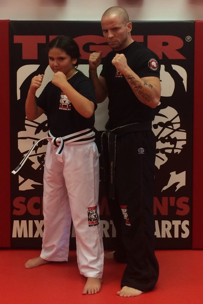 Girl fighter and her instructor Posing in Front of TSMA Logo