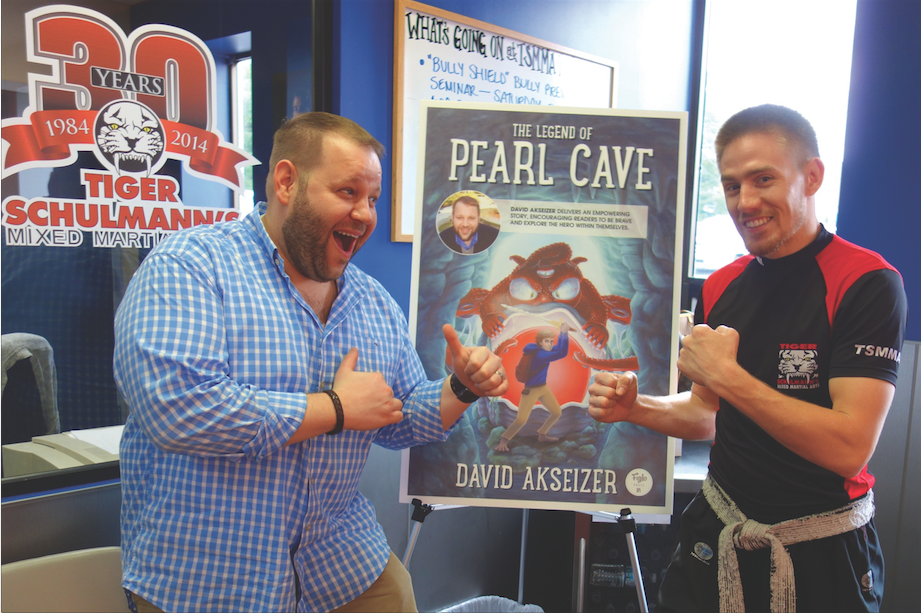 Two Men Smiling in front of Pearl Cave poster at Tiger Schulmann's