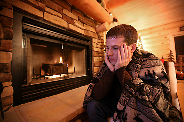 Emotional Boy with blanket sitting next to the fireplace