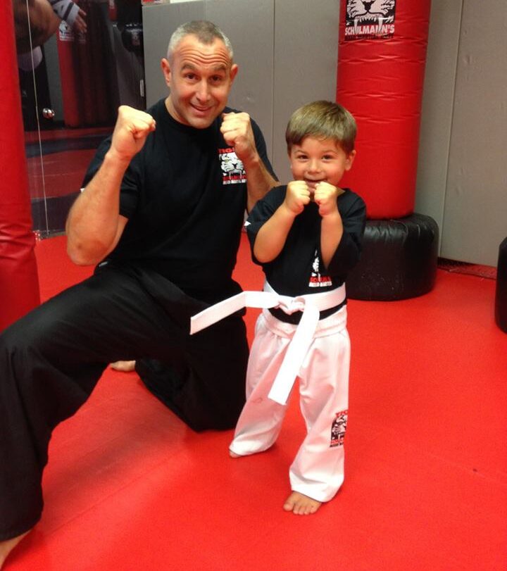 Martial arts instructor and a boy student smiling with fists up at Tiger Schulmann's gym