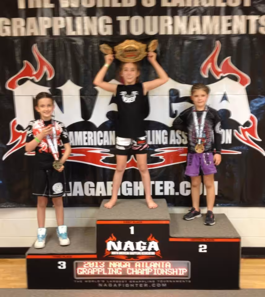 Tiger Schulmann's Martial Arts | TsmmaTampakellyA girl raises NAGA grappling reward with 2nd and 3rd placed girls beside her