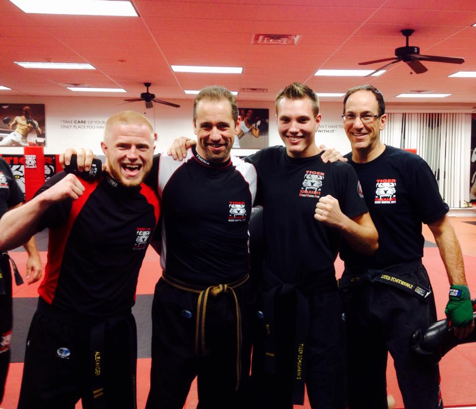 Four Tiger Schulmann's fighters posing in a gym with fists up