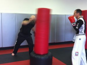Two MMA fighters working out with a red punching bag