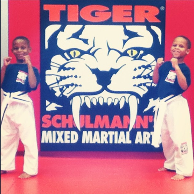 Two Boys Smiling with fists up and the TSMA Logo behind
