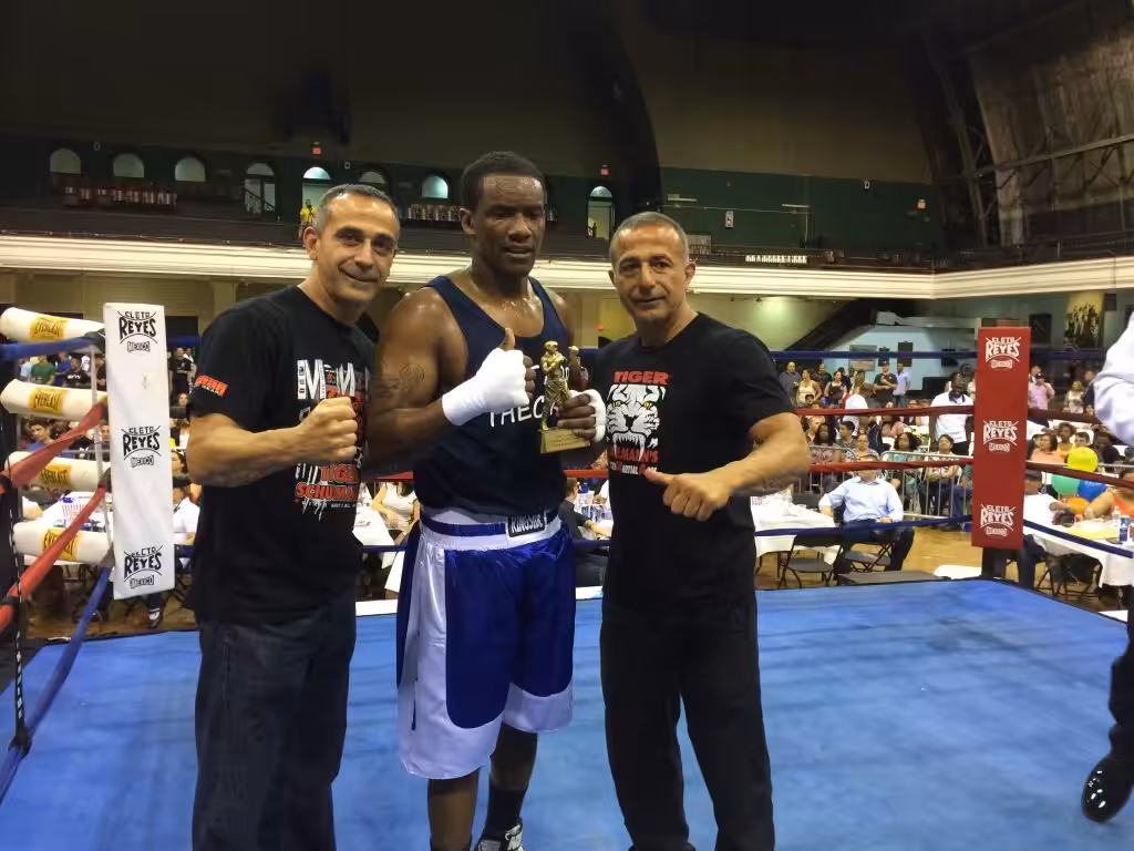 MMA fighter holding a trophy qith his two Tiger Schulmann's team members in ring