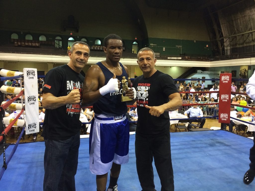 MMA fighter holding a trophy qith his two Tiger Schulmann's team members in ring