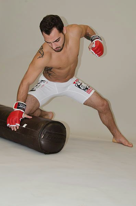 A man in Tiger Schulmann's outfit Punching a brown punching bag