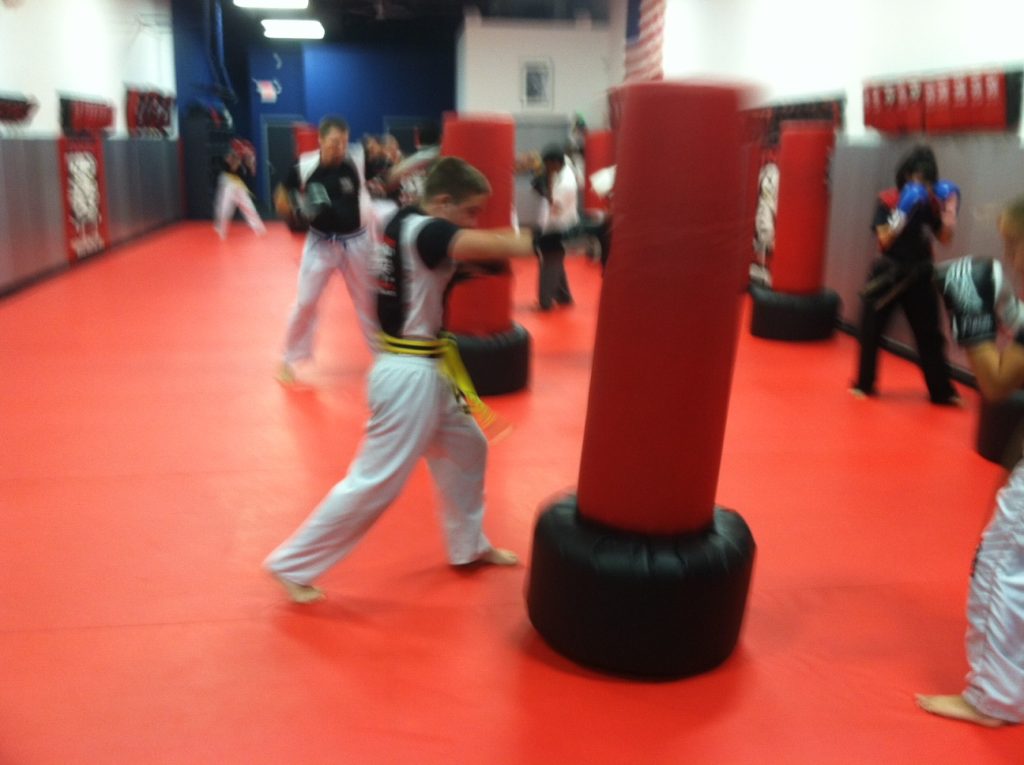 Boy punching a red punching bag at Tiger Schulmann's