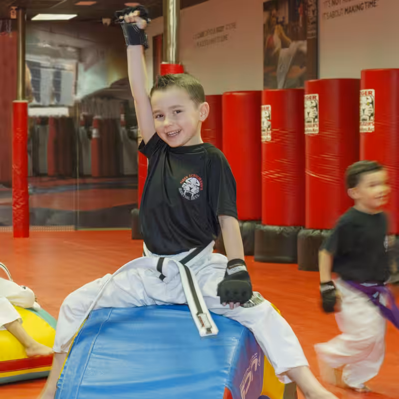 A Boy Raising Hand and smiling on the workout at Tiger Schulmann's gym