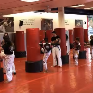 Kids training with kicking bags supervised by instructor
