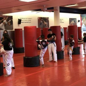 Kids training with kicking bags supervised by instructor