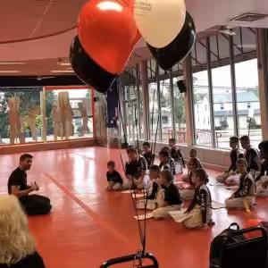 Kids sitting during their martial arts training with baloons beside them