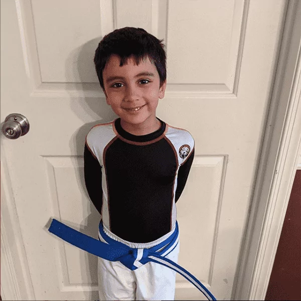 A boy in martial arts clothes standing in front of the door