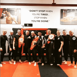 Ten male MMA fighters with championship belts at Tiger Schulmann's Astoria