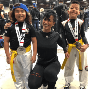 A woman instructor with two boys and their medals at Tiger Schulmann's Chelsea