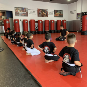 Kids sitting on their knees and listening to martial arts instructor in Glendale