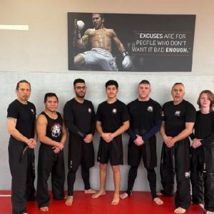 A group of fighters in fron of a wall with motivational qoute in Tiger Schulmann's