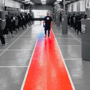 Sensei walking down the middle of the gym while training in progress