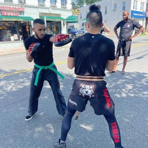 Two fighters sparring and sensei watching them at the street in Manhasset