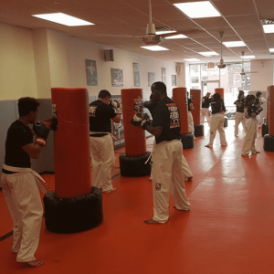 Adults workout using punching bags at Tiger Schulmann's Middle Village