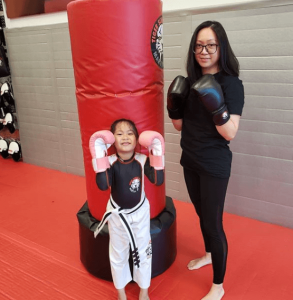 Mother and daughter in front of a punching bag at Tiger Schulmann's gym