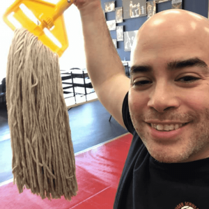 Martial arts instructor holding a mop at Tiger Schulmann's Nanuet