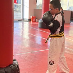 A boy with glasses working out using punching bag at Tiger Schulmann's New Windsor