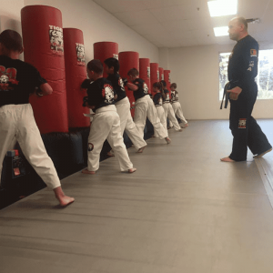 Kids punching bags with their instructor behind at Tiger Schulmann's New Windsor