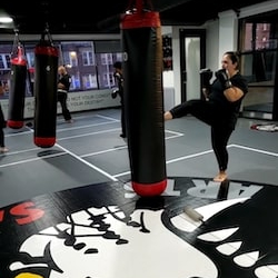 A woman kicking punching bag at Tiger Sculmann's Chelsea