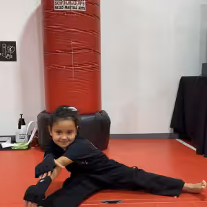 Little girl stretching on the gym floor at Tiger Schulmann's Rockville